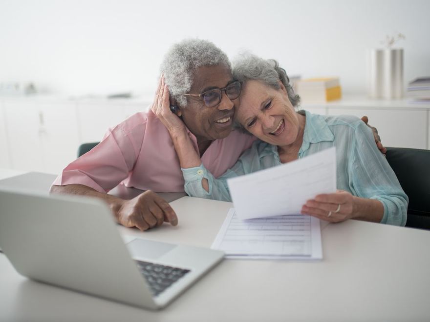 A couple smiling together while reviewing their Medicare plan options at home